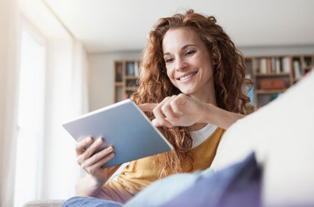 Eine Frau in wohlinger Umgebung mit einem Tablet in der Hand.